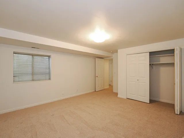 Wall-to-wall carpeting, multiple closets with bi-fold doors, white interior doors, and a window with blinds