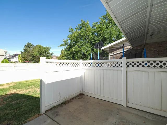 Paved patio space featuring a lattice-topped privacy fence and an awning