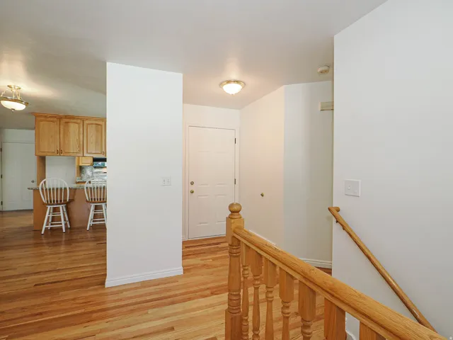 Hardwood flooring throughout, natural wood cabinetry, light-toned walls, and a white paneled door