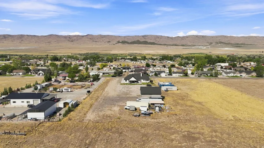 Expansive land parcel with surrounding residential properties, several outbuildings, and distant mountain backdrops