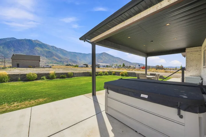 Covered patio with integrated lighting and concrete flooring, featuring a spa