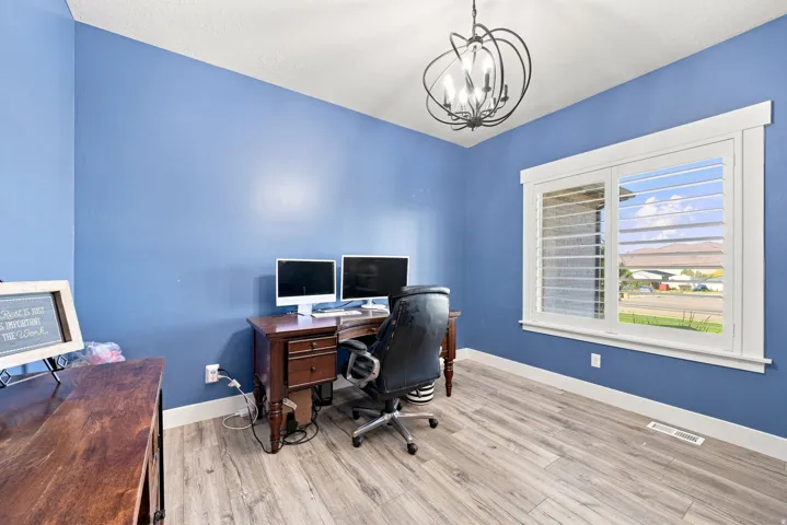 Recessed lighting and a decorative chandelier illuminate this space with wood-finish flooring