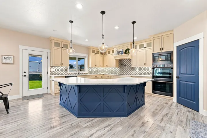 Kitchen featuring a large central island with a light-toned countertop, a stylish tiled backsplash, and recessed lighting