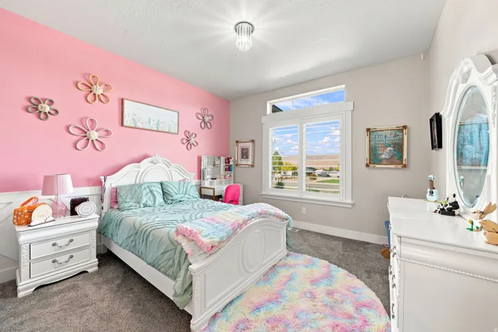 Carpeted room featuring a large window with plantation shutters, a transom window, white trim, and a decorative ceiling light fixture