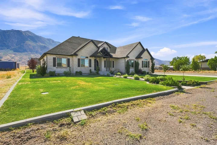 Brick exterior with dark shutters, gabled roofline, covered entry, and a manicured lawn with established landscaping