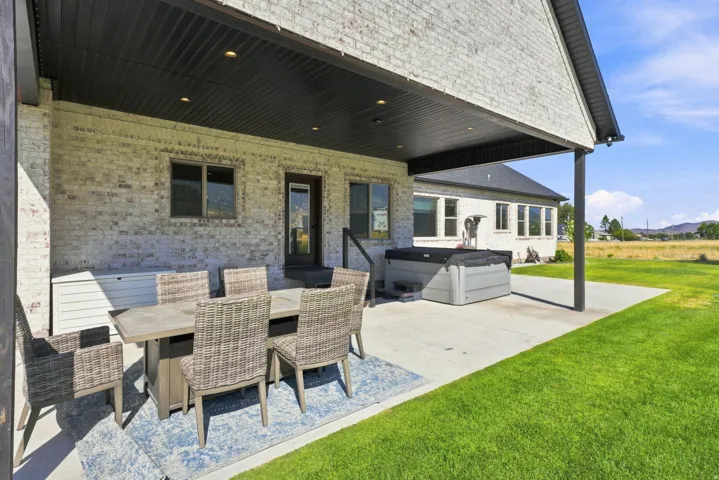 Covered patio with recessed lighting, brick exterior, and a built-in spa