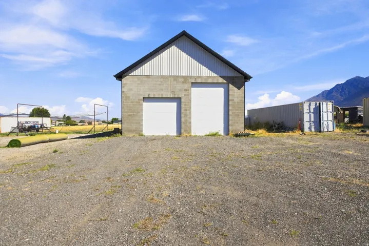 Spacious storage structure featuring a stone facade with metal roof, dual large garage doors, and metal siding accents