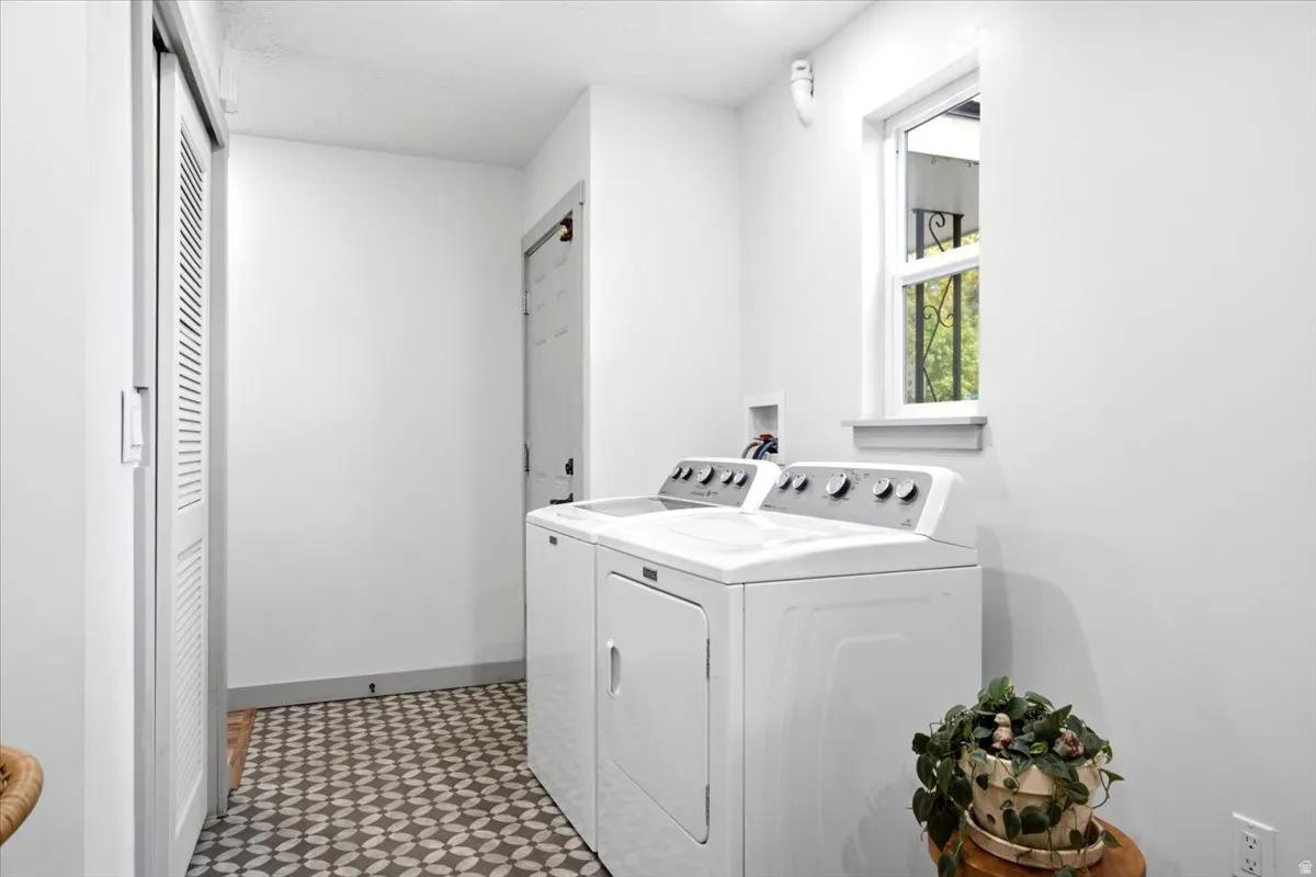 Laundry area featuring patterned flooring, a window with exterior scrollwork, and a bi-fold louvered door