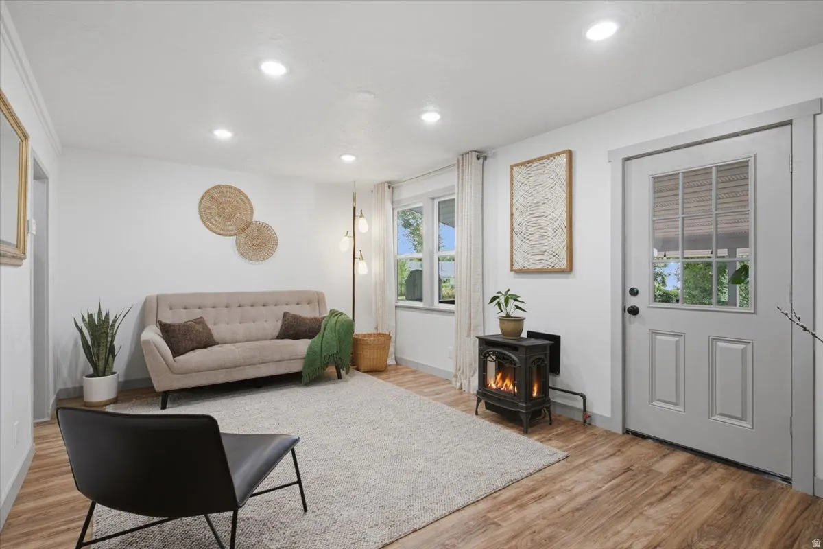Recessed ceiling lighting, laminate wood-finish flooring, white walls, and a paneled door