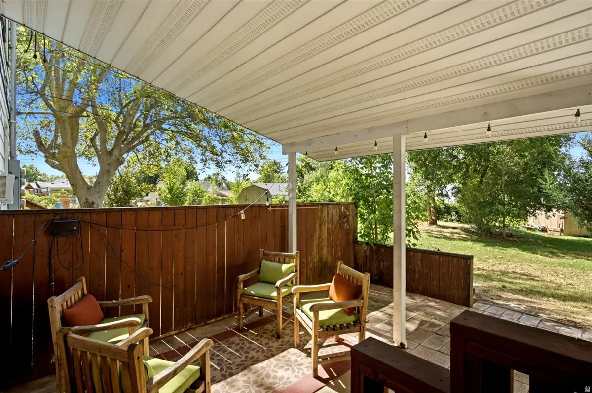 Covered patio with a paneled ceiling, wooden fence, and paved flooring