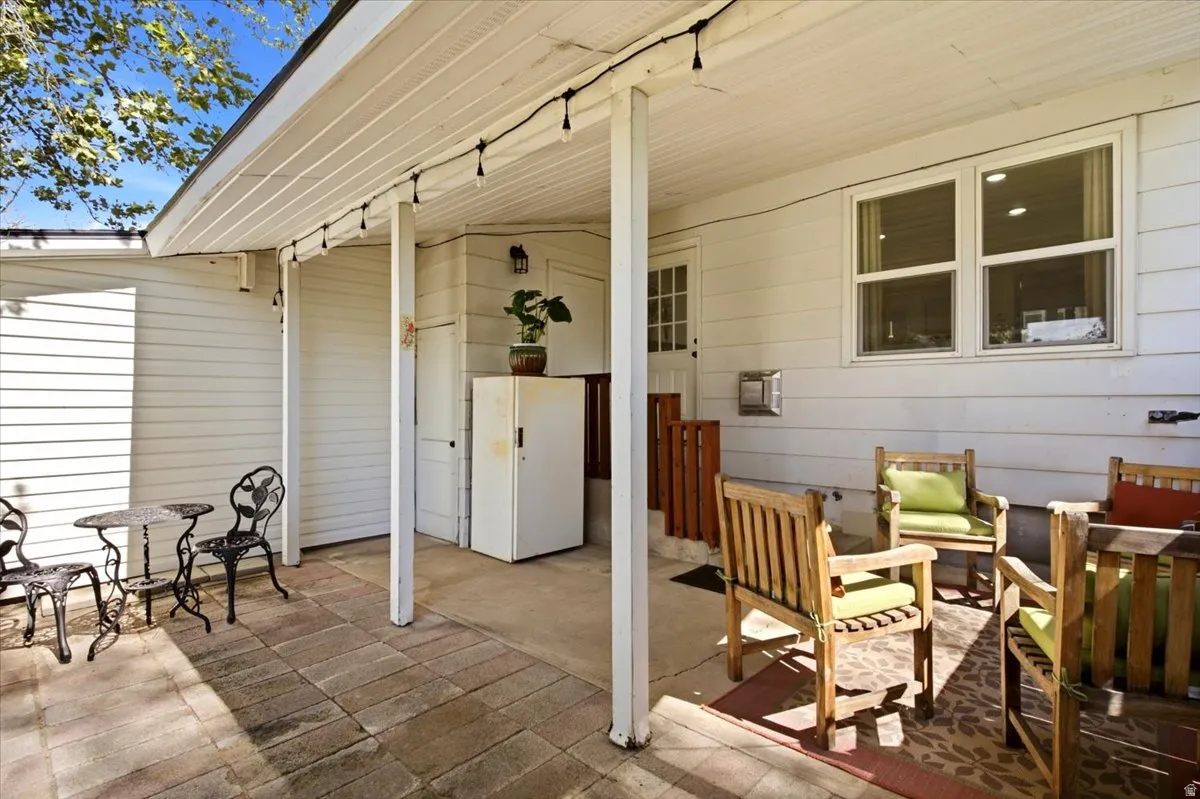 Covered patio area featuring a paver stone surface, white siding, and a rear door with multiple window panes