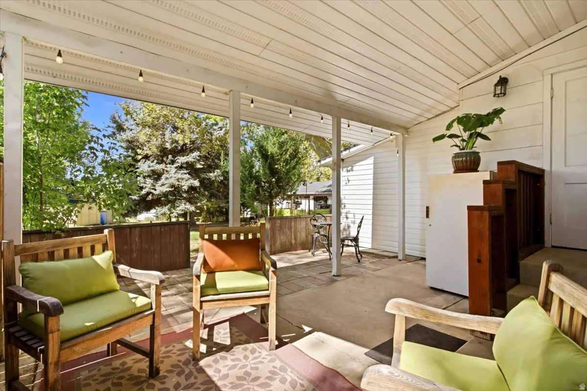 Covered patio with concrete flooring, wood privacy fencing, and string lighting