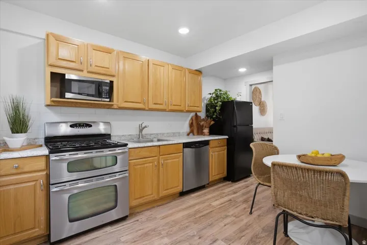 Kitchen featuring wood-finish cabinetry, stainless steel appliances, white subway tile backsplash, and light-toned countertops