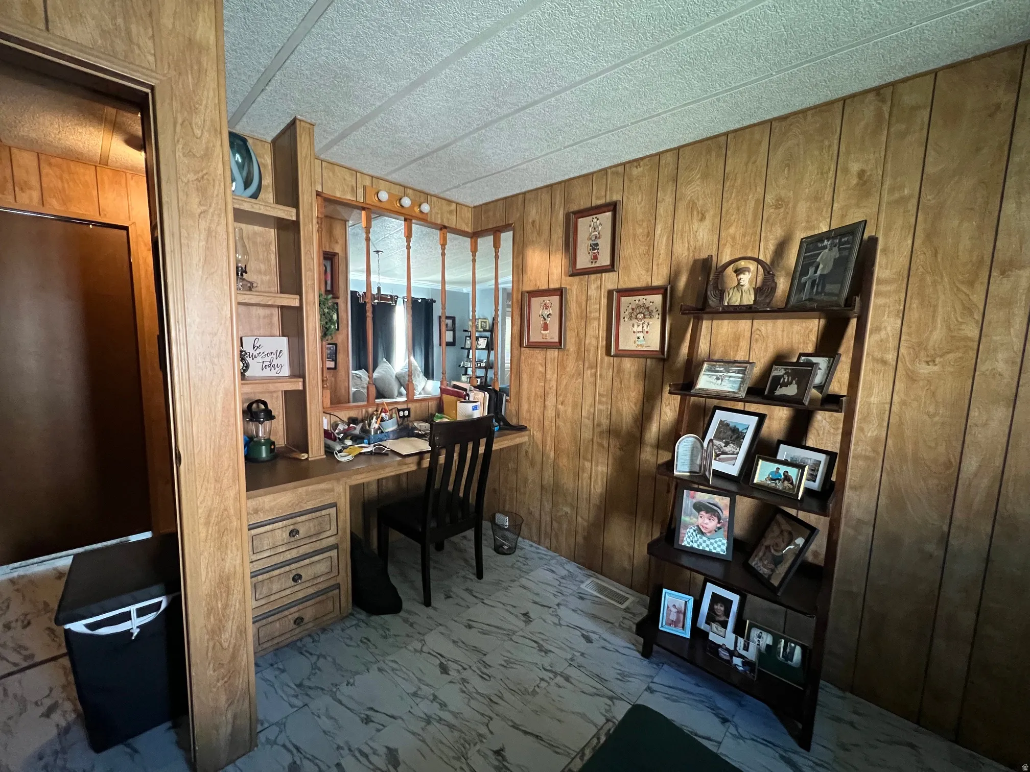 Built-in desk with integrated shelving and storage drawers, wood-finish wall paneling, and patterned flooring