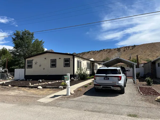 Single-story residence featuring a carport, front yard landscaping with rock accents, and a paved driveway