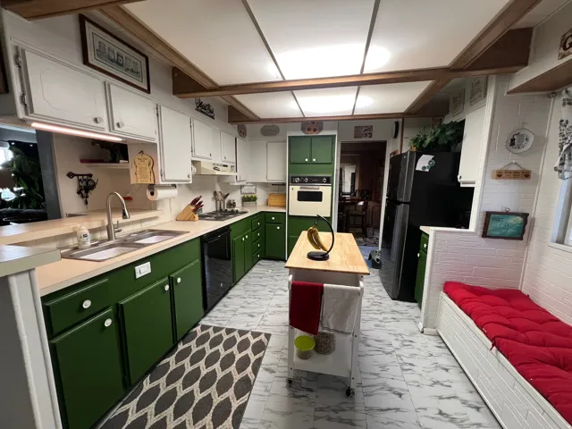 Kitchen featuring wood-finish ceiling beams, white upper cabinetry, built-in oven