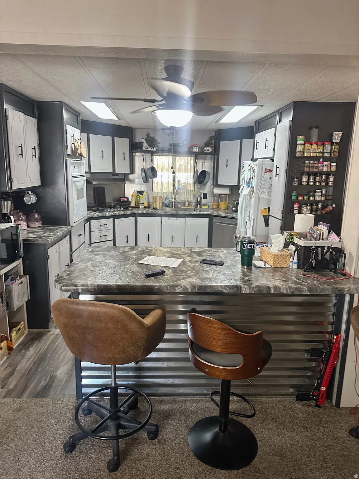 Modern kitchen featuring stainless steel appliances, granite-style countertops, white cabinetry with hardware accents, and a center island with seating
