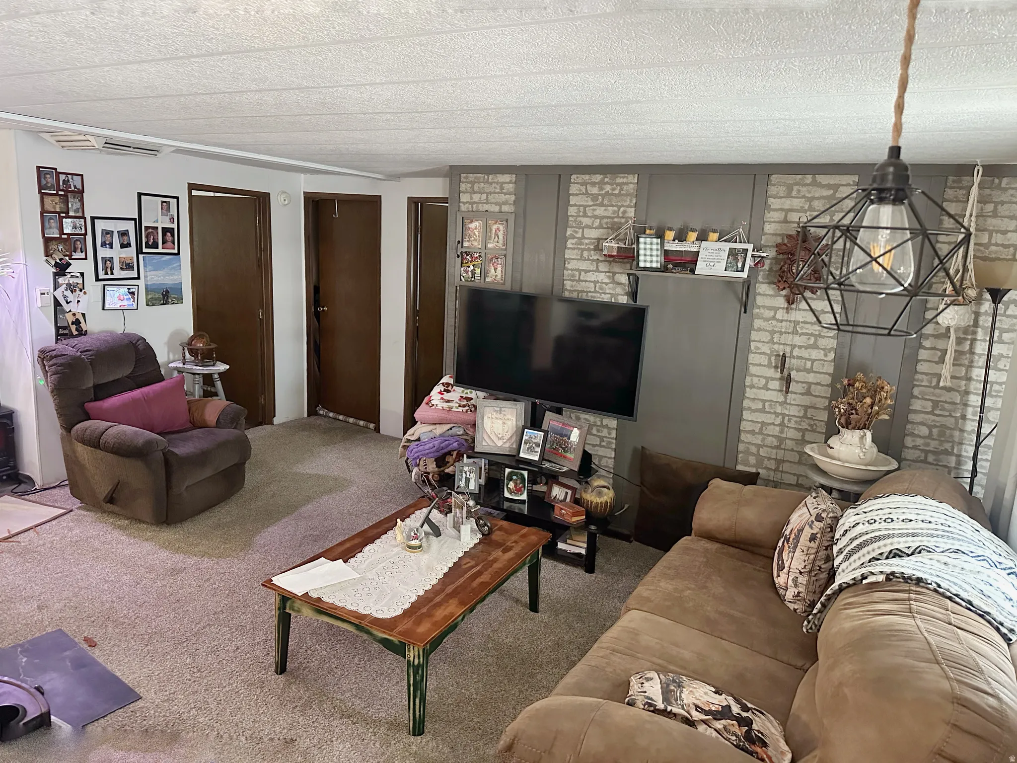 Textured ceiling, carpet flooring, interior doors, and a decorative wall treatment featuring brick-style paneling