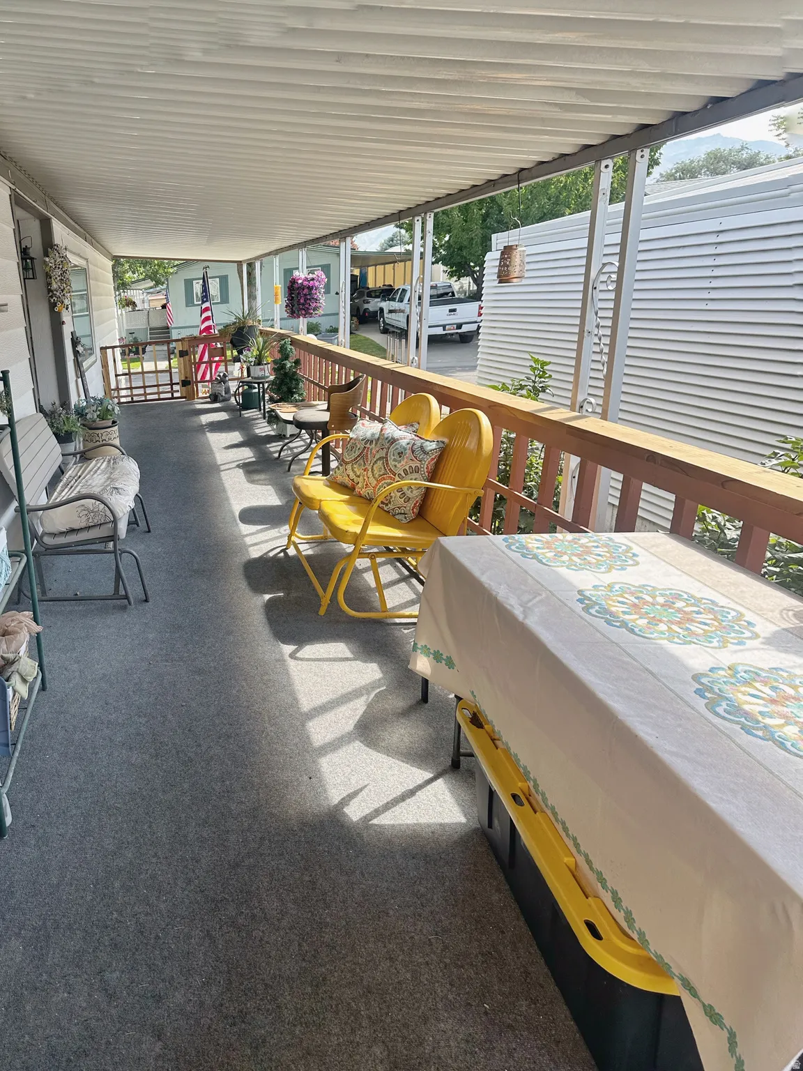 Covered front porch featuring composite decking, wood-finish railings, and corrugated metal roof providing sheltered outdoor space