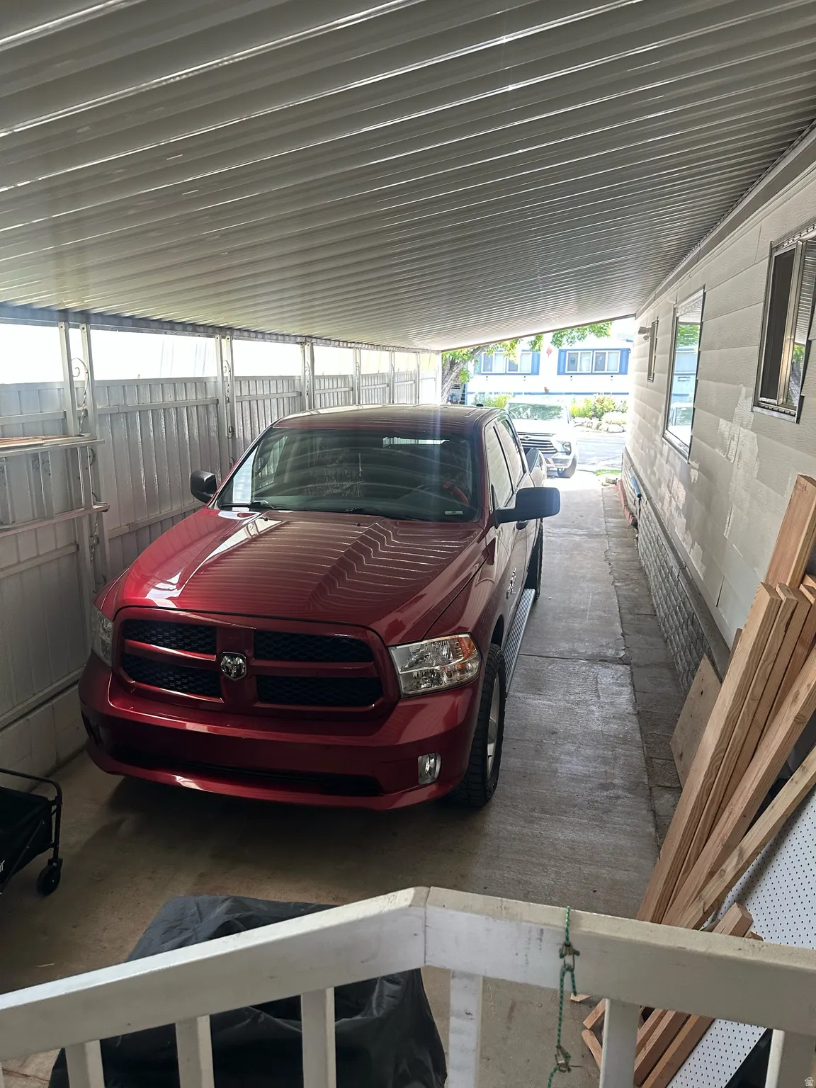 Covered carport with a concrete slab, supporting metal framework, and corrugated ceiling panels