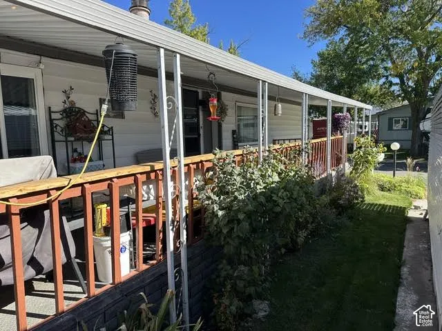 Covered porch with white siding, red painted railing, and surrounding landscaping
