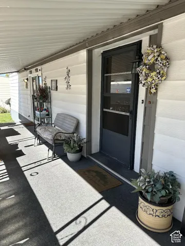 Covered porch with light-colored siding and a dark screen door