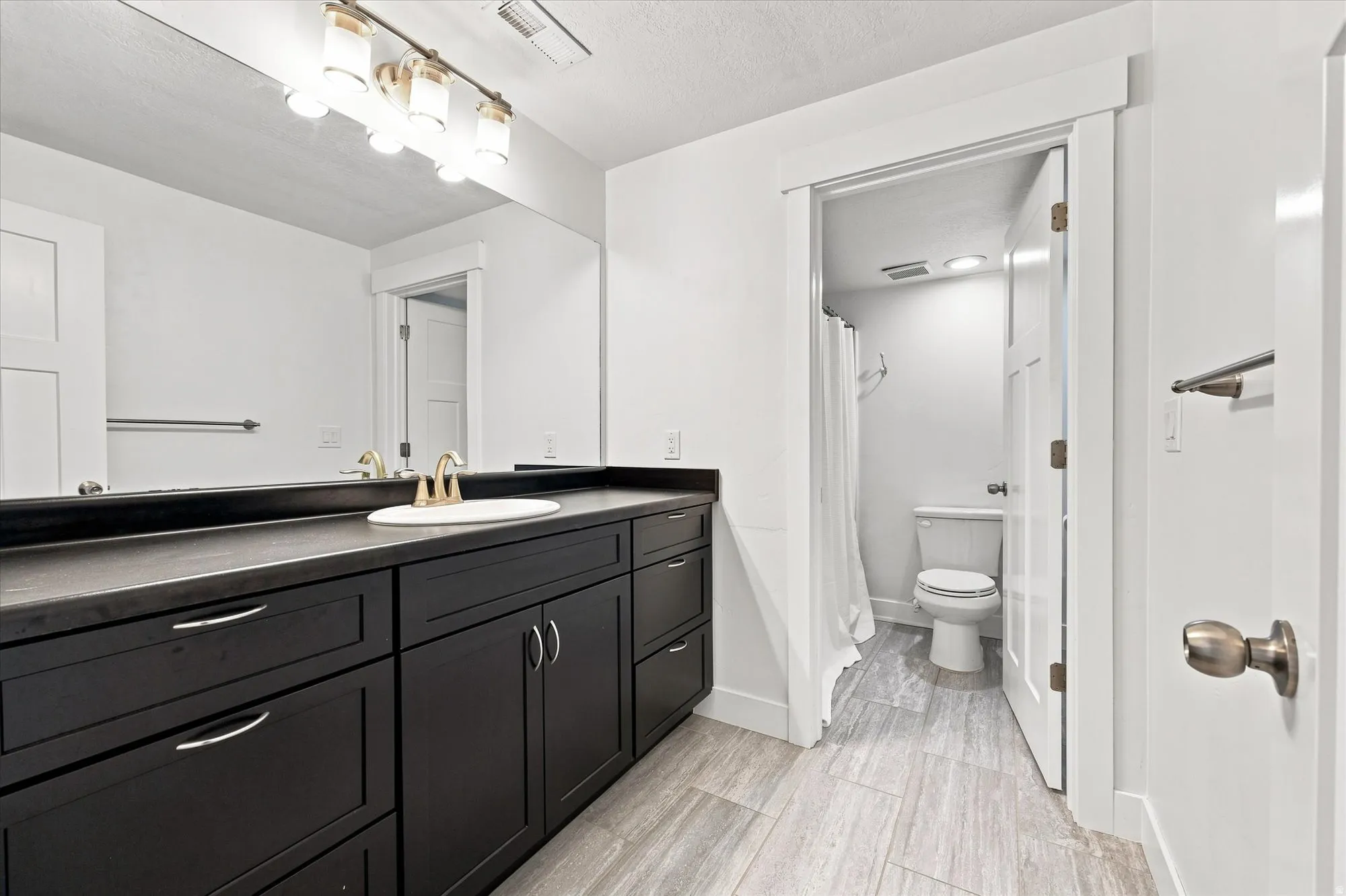 Dark wood-finish vanity with ample storage and stone-finish countertop