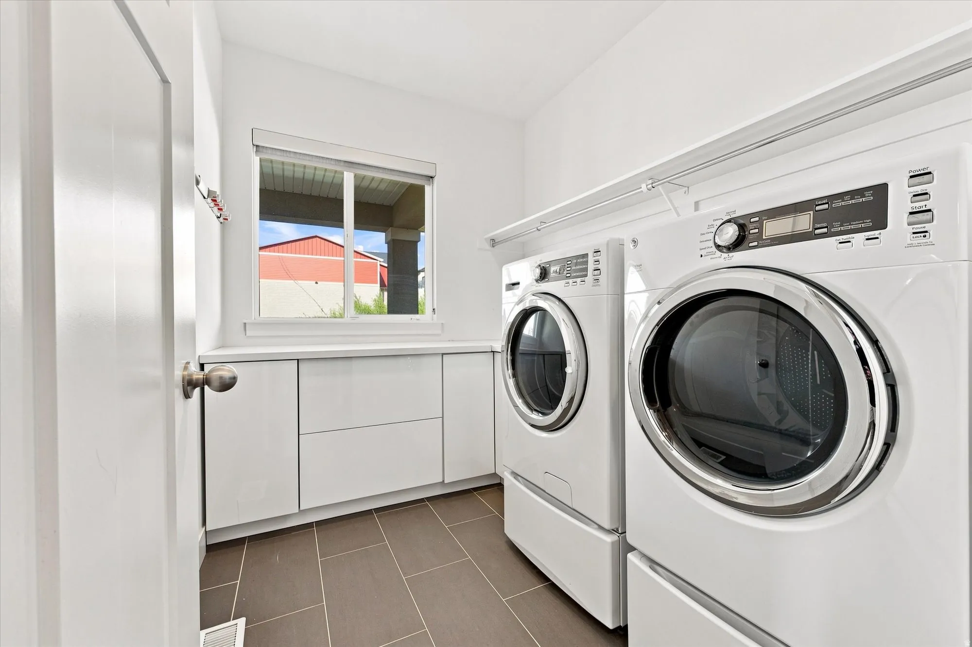 Integrated laundry appliances, durable tile flooring, built-in cabinetry, and a window for natural light