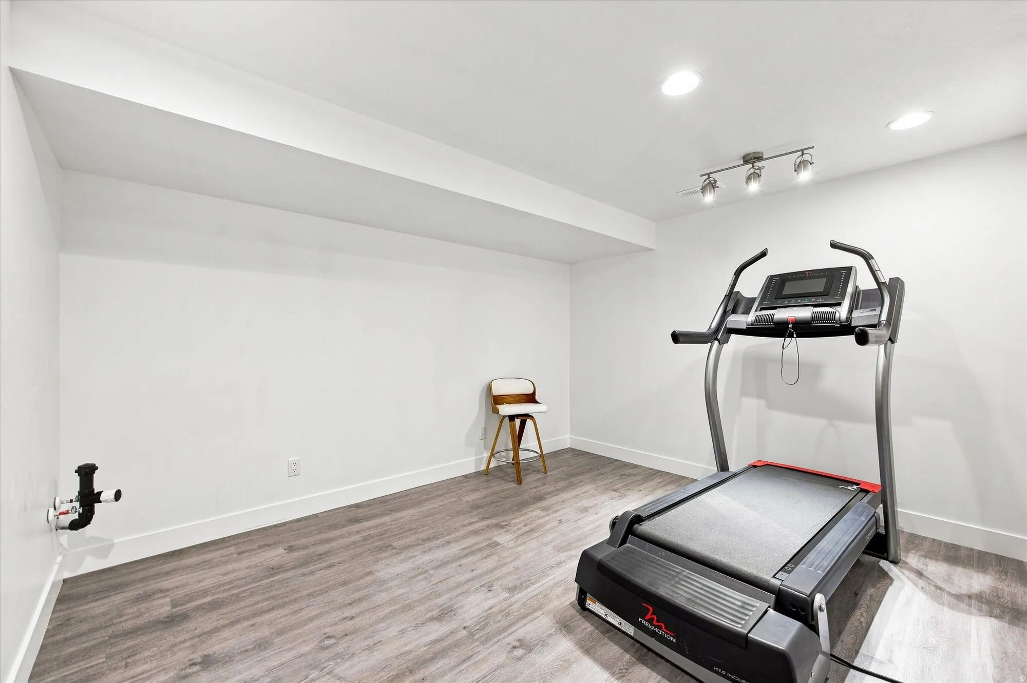 Recessed ceiling lighting, track lighting, wood-finish flooring, and white painted walls