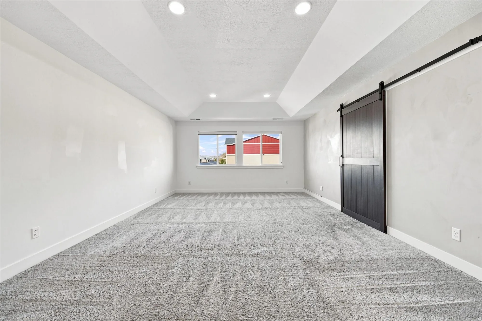 Recessed lighting, tray ceiling, carpeted flooring, window, and barn door