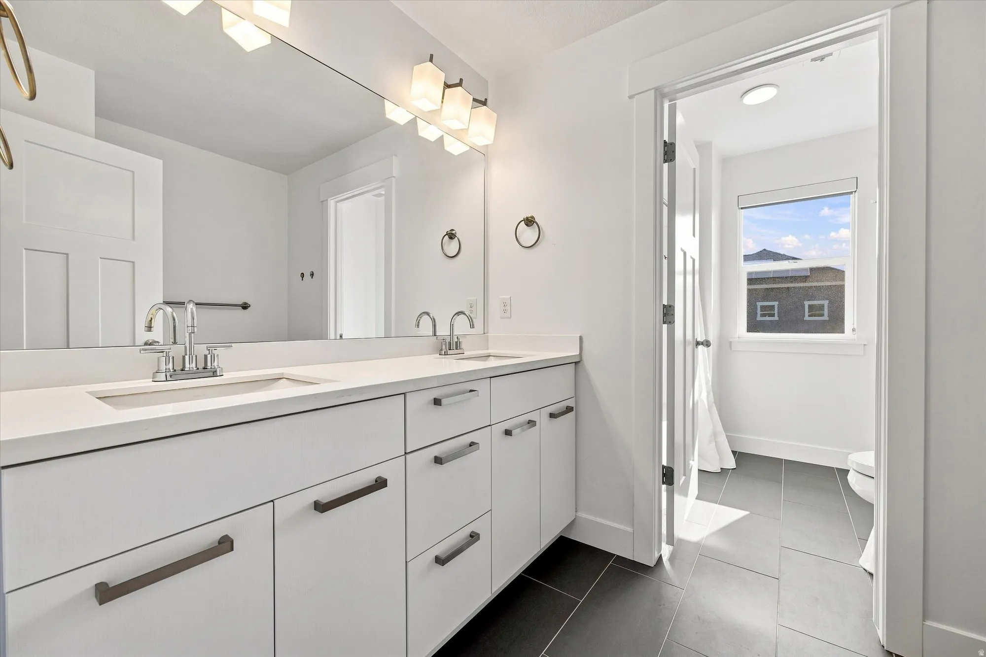Dual vanity with integrated sinks, light-toned countertop, and white cabinetry