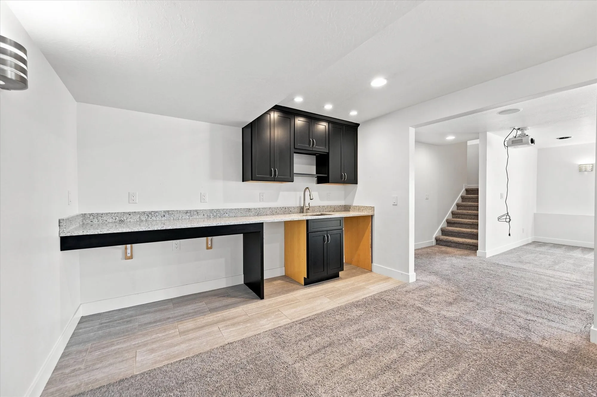 Built-in wet bar with dark cabinetry, integrated sink, and light-toned countertop