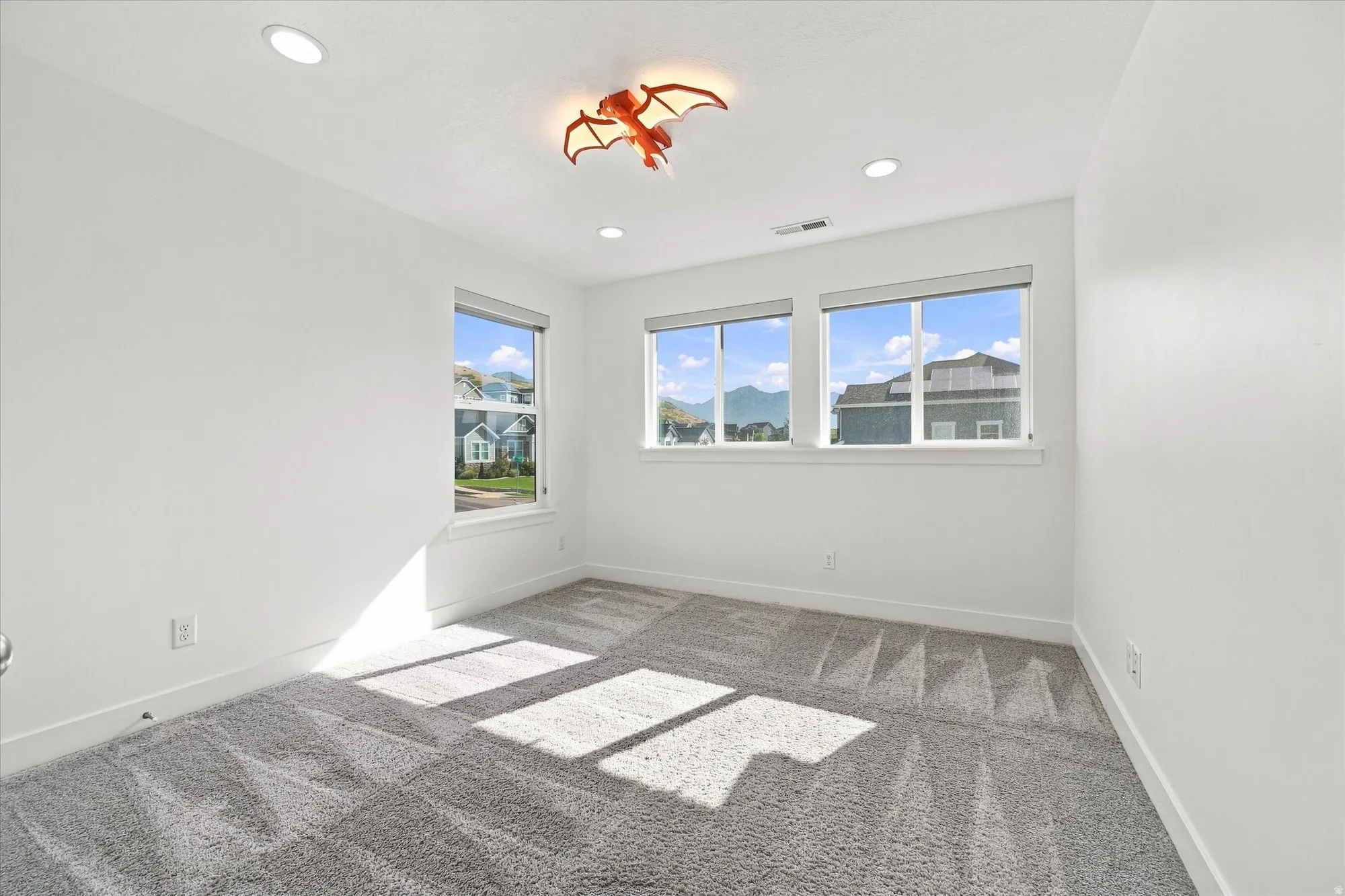 Room featuring recessed lighting, a ceiling-mounted light fixture, multiple windows, wall-to-wall carpeting, and white walls
