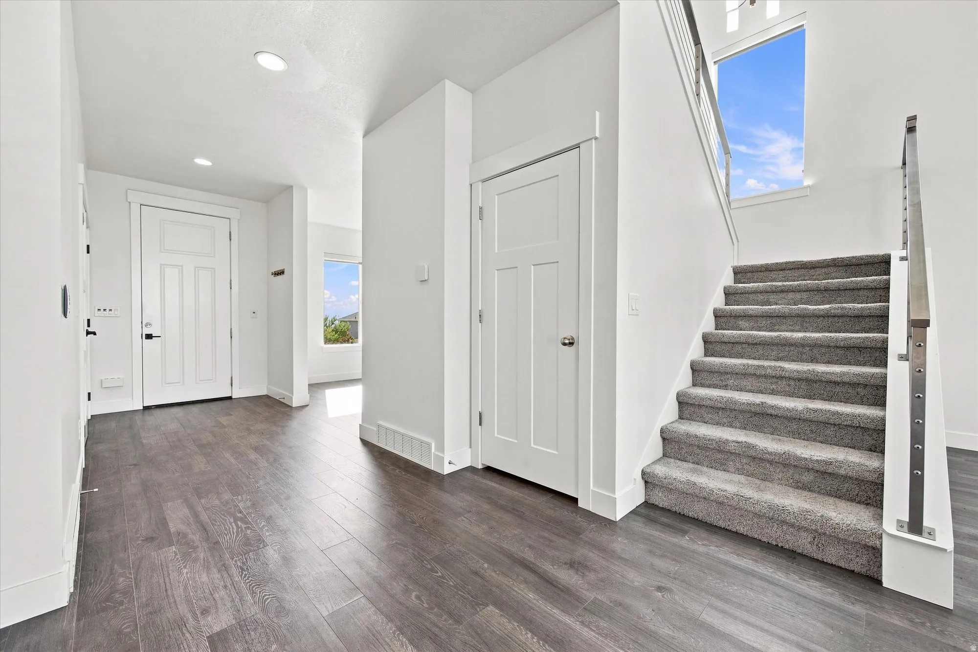 Foyer featuring wood-finish flooring, recessed lighting, and a white paneled entry door