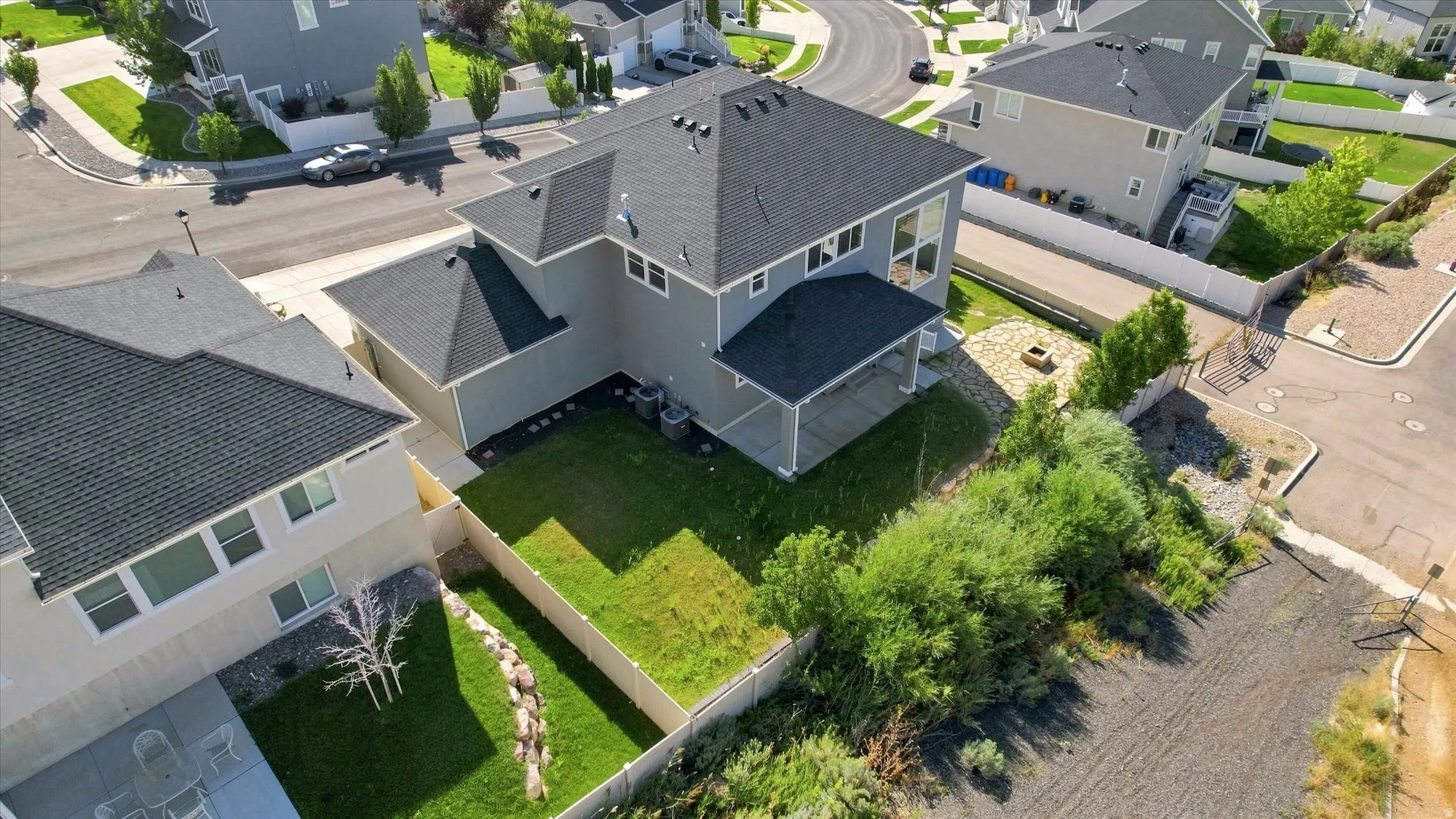 Well-maintained residential property featuring a covered patio, landscaped yard, and a stone fire pit area