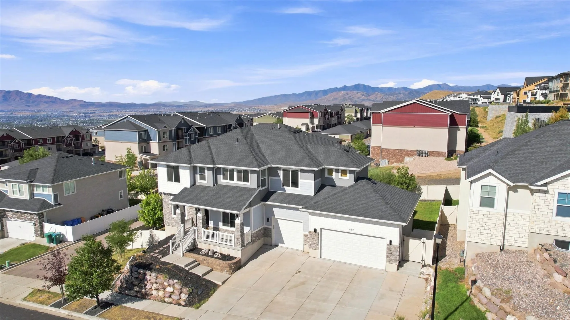 Light gray exterior with stone accents, covered front porch, and an attached two-car garage