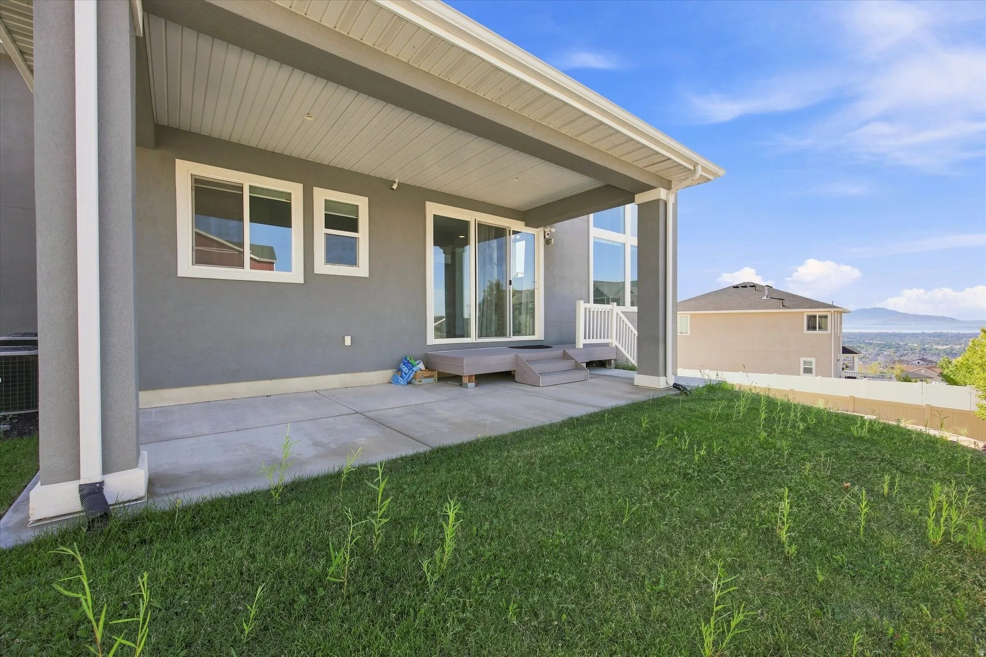 Covered patio with concrete flooring, multi-pane windows, and a sliding glass door