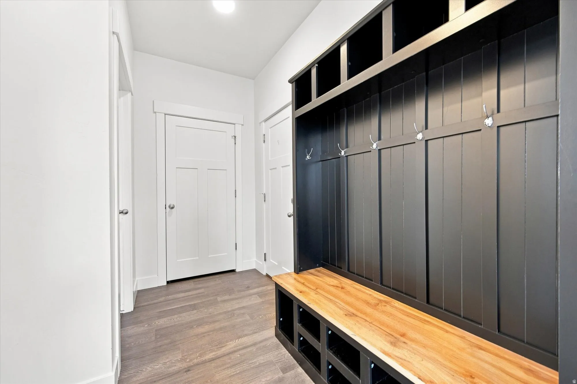 Entryway featuring a built-in mudroom bench with wood-finish seating, individual storage cubbies, and integrated coat hooks