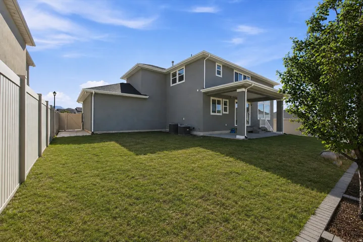 Spacious backyard, full vinyl fencing, covered patio, and a light-colored privacy fence