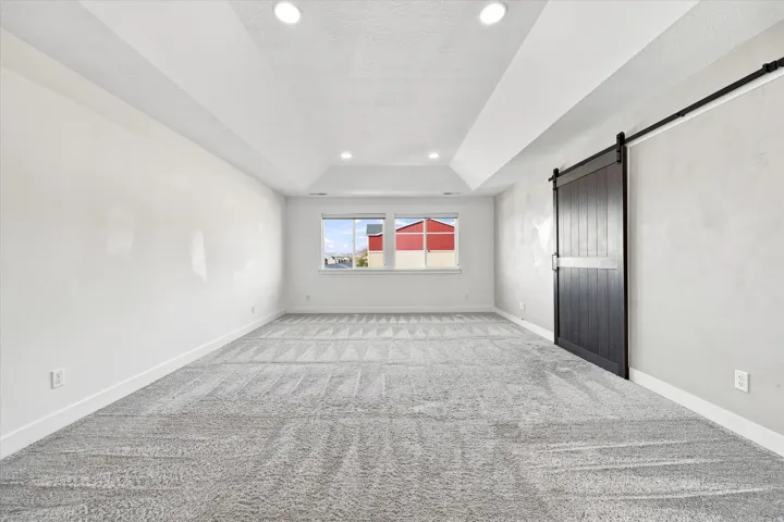 Recessed lighting, tray ceiling, carpeted flooring, window, and barn door