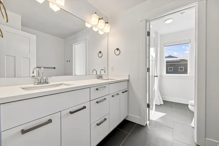 Dual vanity with integrated sinks, light-toned countertop, and white cabinetry