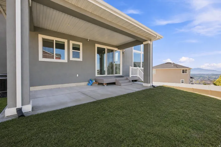 Covered patio with concrete flooring, multi-pane windows, and a sliding glass door