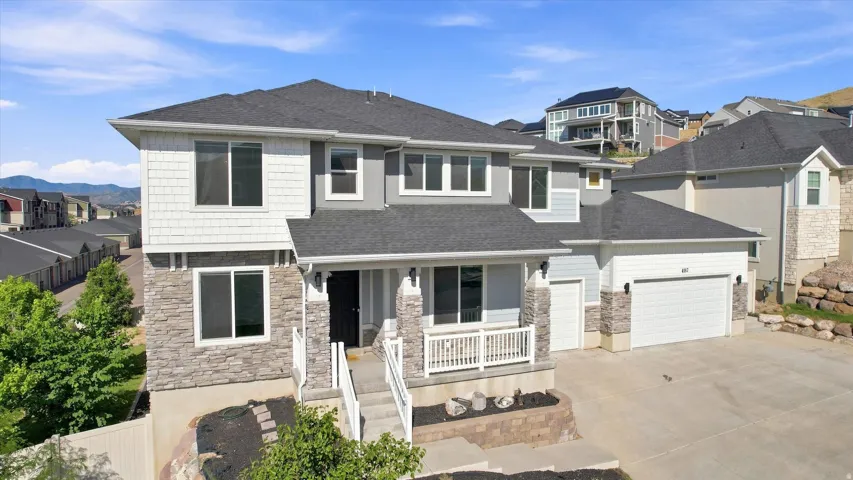 Two-story residence featuring a dark gray roof, light gray siding, and stone accents