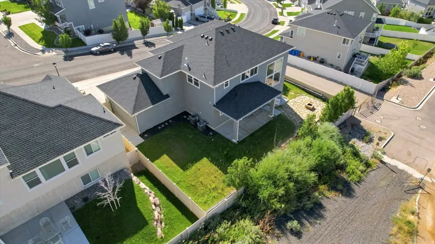 Well-maintained residential property featuring a covered patio, landscaped yard, and a stone fire pit area