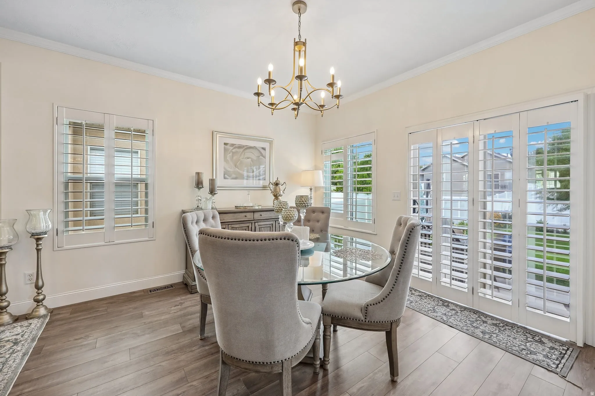 Recessed lighting, crown molding, wood-finish flooring, white plantation shutters, and a glass-paneled patio door