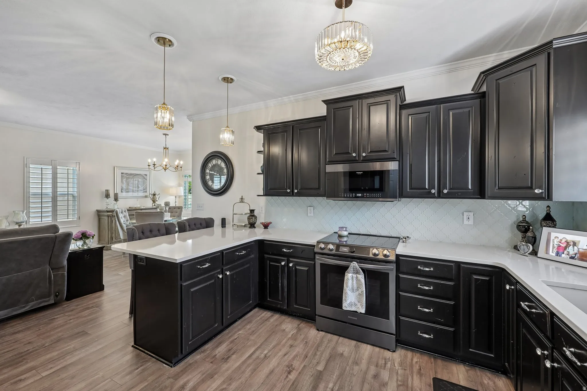 Kitchen featuring dark wood-finish cabinetry, white countertops, herringbone tile backsplash, and stainless steel appliances