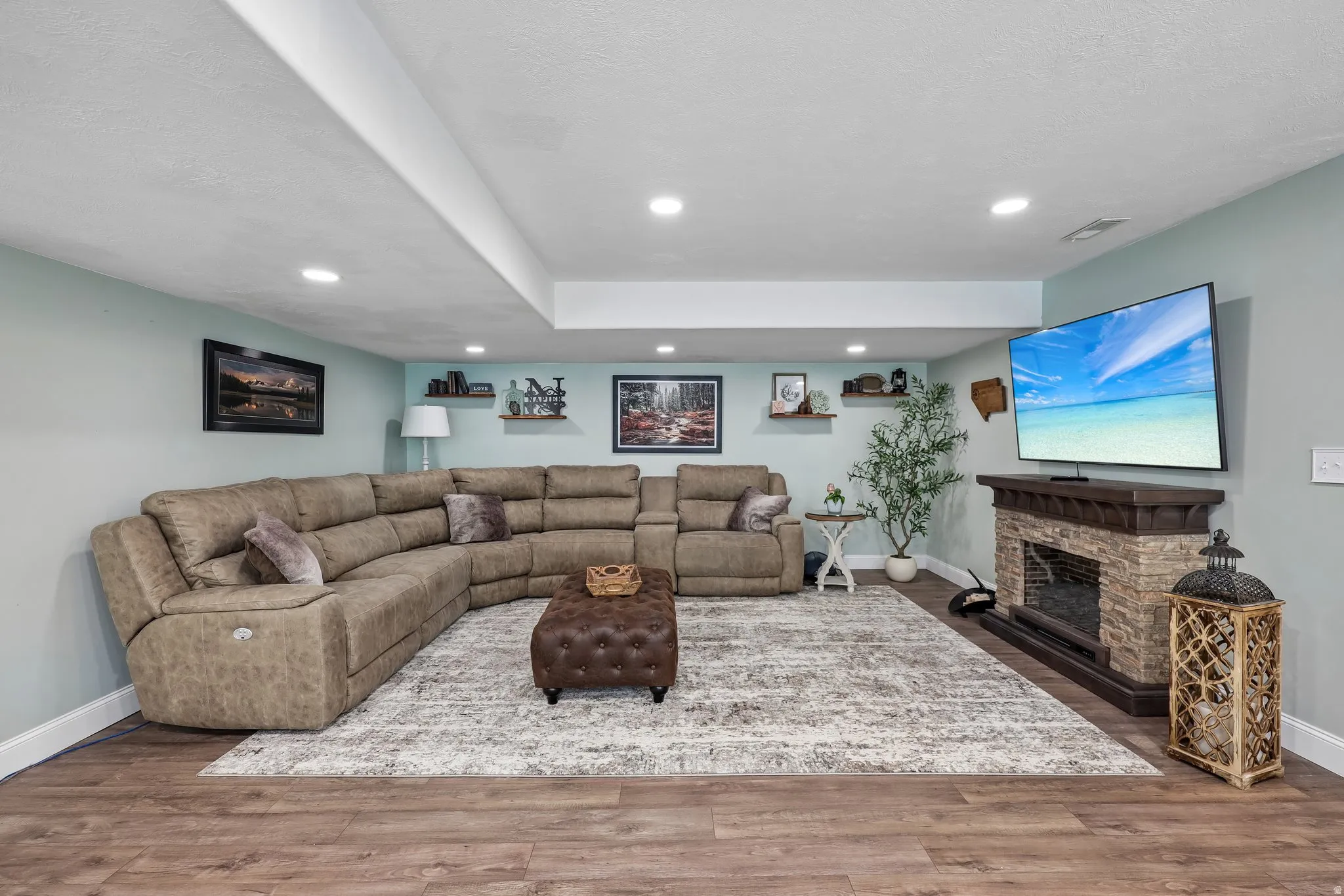 Wood-finish flooring, recessed lighting, built-in shelving, and a stone-clad fireplace with a wood mantel
