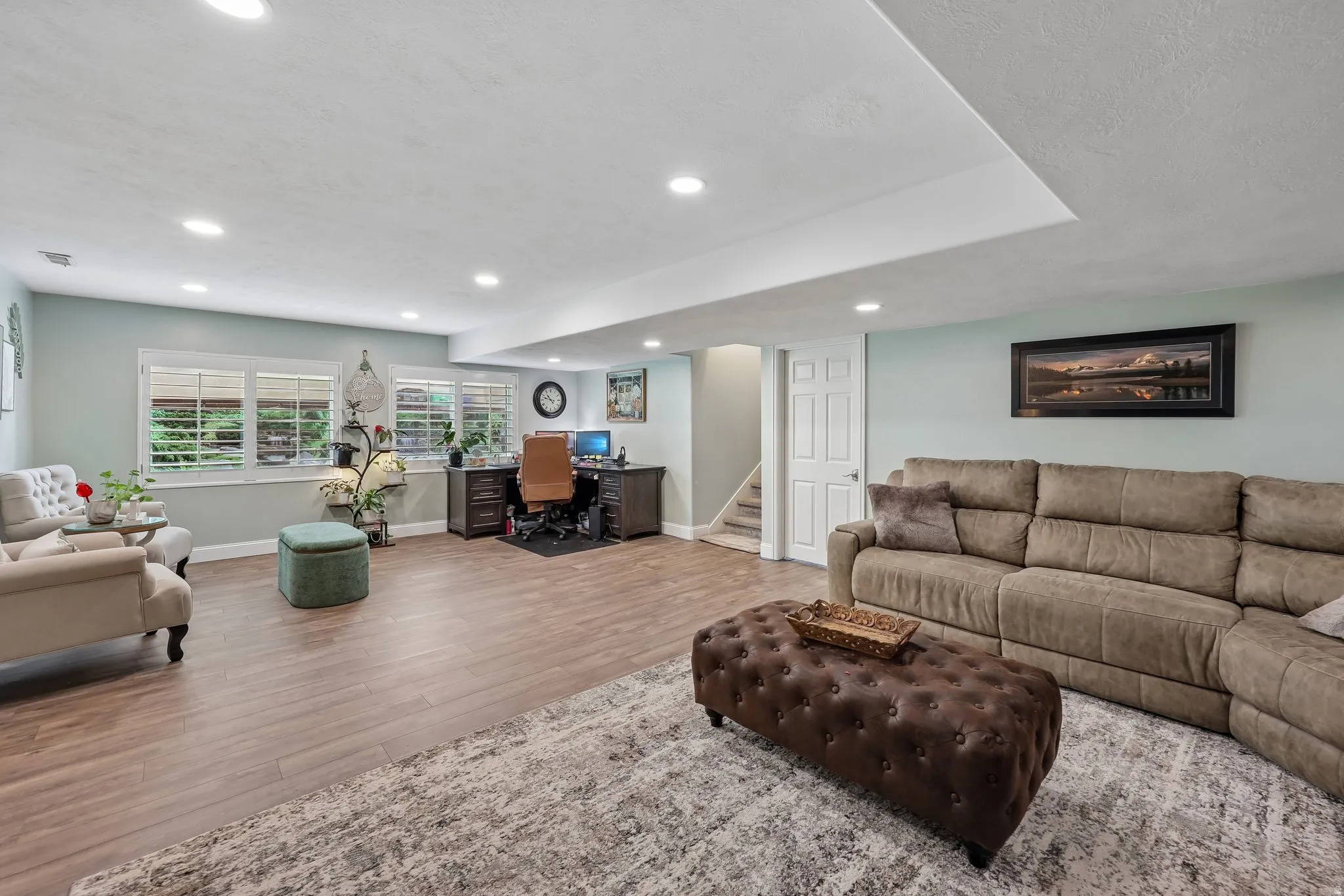 Recessed lighting, wood-finish flooring, multiple windows with plantation shutters, built-in desk cabinetry, and a paneled interior door