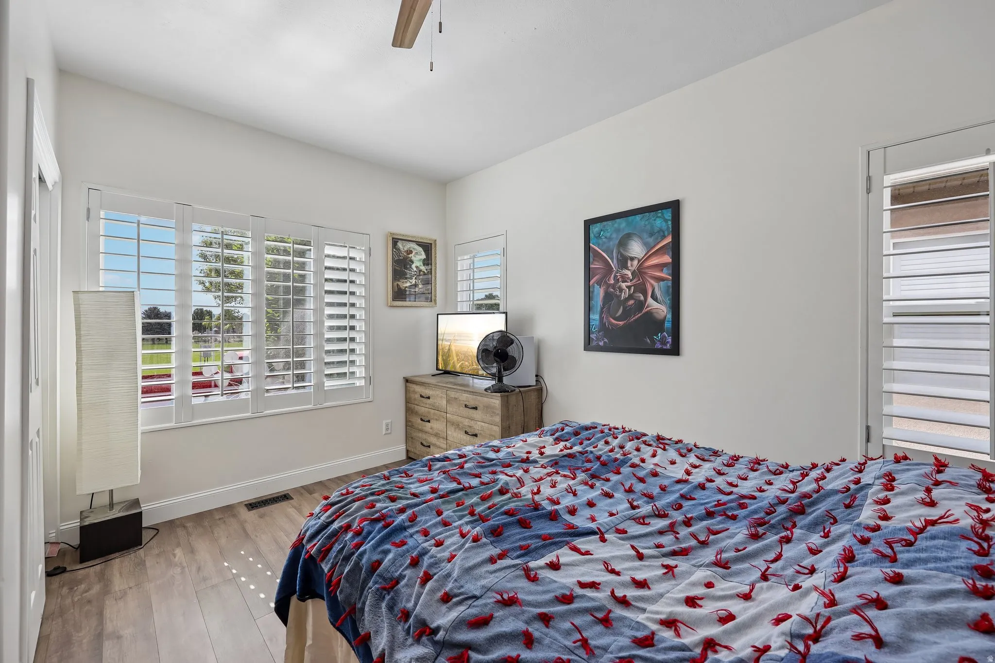 White walls, wood-finish flooring, and white plantation shutters on multiple windows
