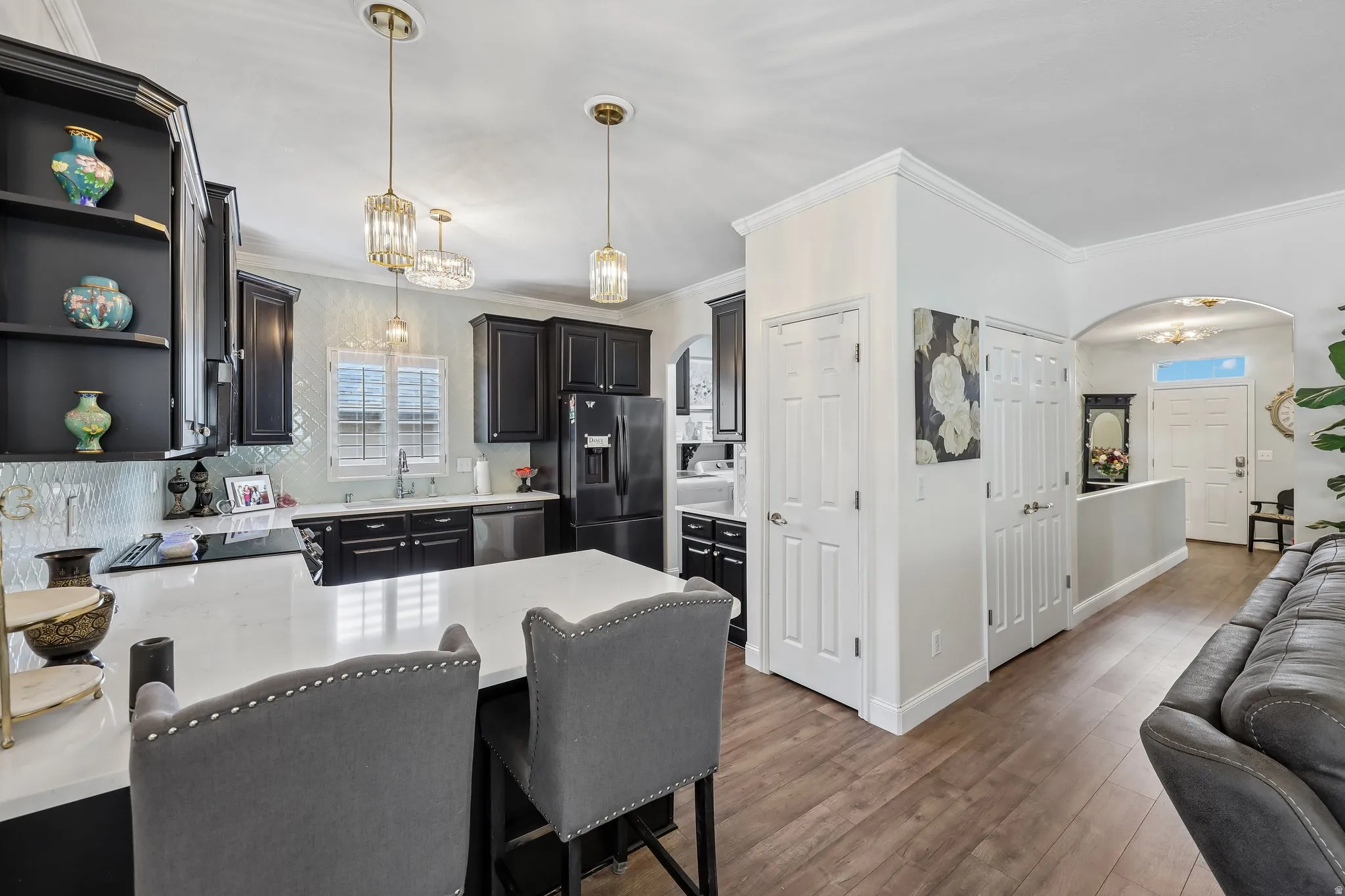 Kitchen featuring a central island with white countertop, black cabinetry, and a tile backsplash